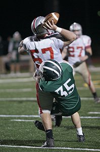 Dylan Mahoney (35) wraps up the New Bedford quarterback for a sack. Photo by Paul Goldburg
