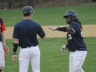 Needham’s Dakari Cox (23) gets a fist bump from his first base coach following an RBI single in the top of the seventh inning. Photos by Michael Flanagan