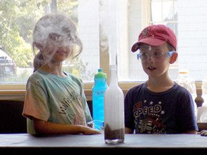 Two volunteers help bring the ScienceTellers pirate story to life by mixing manganese dioxide and hydrogen peroxide to create a fountain of water vapors. Photos by Laura Drinan