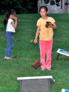 Kids narrow their focus to aim the bean bag in the corn hole toss. Photo by Brooke Baker