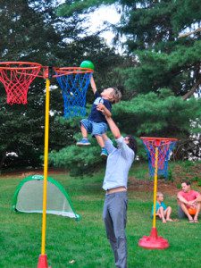 A dad lifts his son up tall to dunk a basket on the basketball hoops. Photo by Brooke Baker