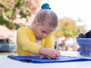 A child traces her hand onto a backpack, which will later be given to a homeless adult, at the ‘I’ve Got Your Back’ station.