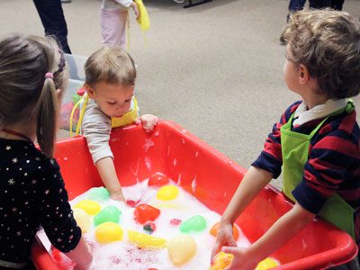 For a sensory development activity, participants at the Dover Town Library’s ‘Super Awesome Fun Time’ play with toys in soapy water.