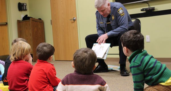 Children crowd around Dover Police Department’s Chief McGowan at the library’s ‘Local Hero Storytime.’