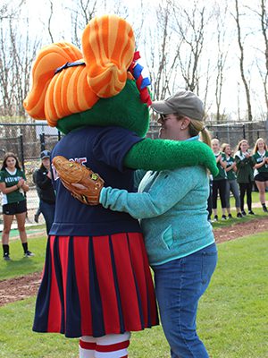 Theresa Martin, a retired Army captain and former Westwood softball player, gets a hug from Tessie, Wally the Green Monster’s younger sister, for throwing the first pitch of the season.