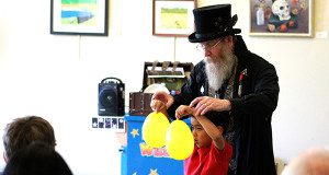 Ed the Wizard helps a young volunteer from the audience with a magic trick.  Photos by Daniel Curtin