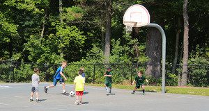 Kids play the beautiful game on the basketball court at the elementary school.