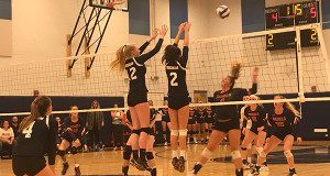 Women's volleyball game with players jumping.