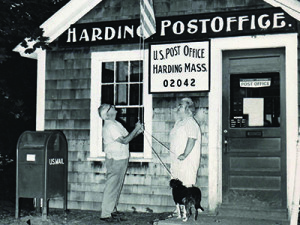Harding PO 02042 (952k): Tom and Elizabeth Sweeney, with their dog "Heidi," lower the American flag for the final time on the wooden 82 Harding Street post office.