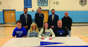 Medfield’s Jaimee Hirschfeld (middle) poses with her family and coaches after signing her NLI to run track at Assumption College.