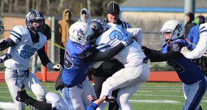 Dover-Sherborn’s James Wirth (16), Leo Jalali (77) and Martin Brault (53) gang-tackle Medfield’s Colby Gonser. 