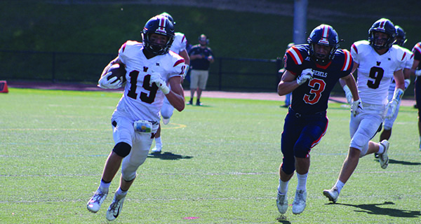 When Teddy Komjathy (19) is not dominating the face-off X, he can be found running routes and scoring touchdowns for Wellesley High football as he is pictured here against Walpole in mid-September.  Photos by Michael Flanagan