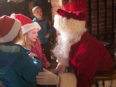 Santa Claus listens to the wishes of two girls.