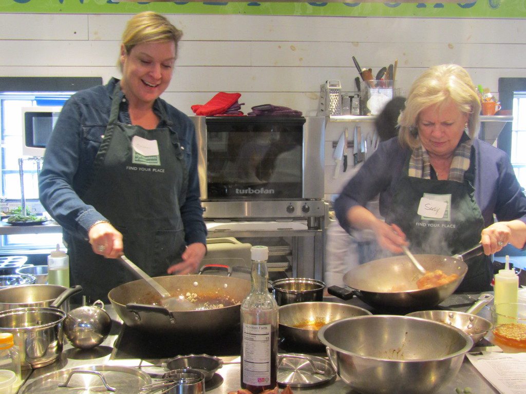 Students Brooke and Susy try their hand at  cooking lemongrass chicken.