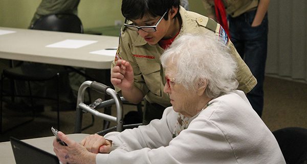 A scout helps a senior add a contact at Saturday’s Tech Tips session.