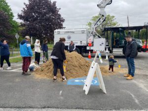 Children playing in sand pile by truck.